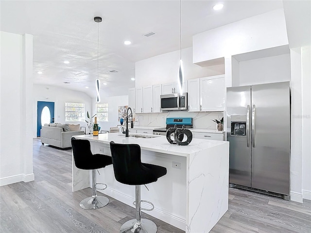 kitchen with stainless steel appliances, visible vents, decorative backsplash, light wood-style floors, and a sink