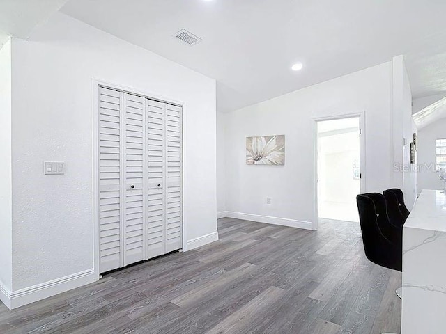 interior space with lofted ceiling, recessed lighting, wood finished floors, visible vents, and baseboards