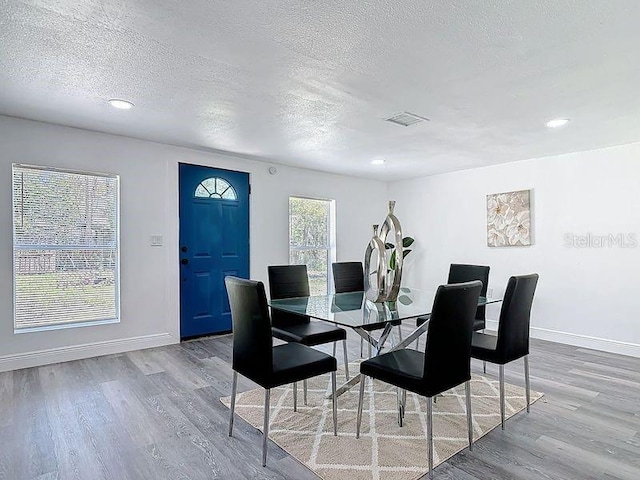 dining room featuring a textured ceiling, baseboards, and wood finished floors