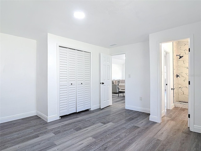 unfurnished bedroom featuring a closet, visible vents, baseboards, and wood finished floors