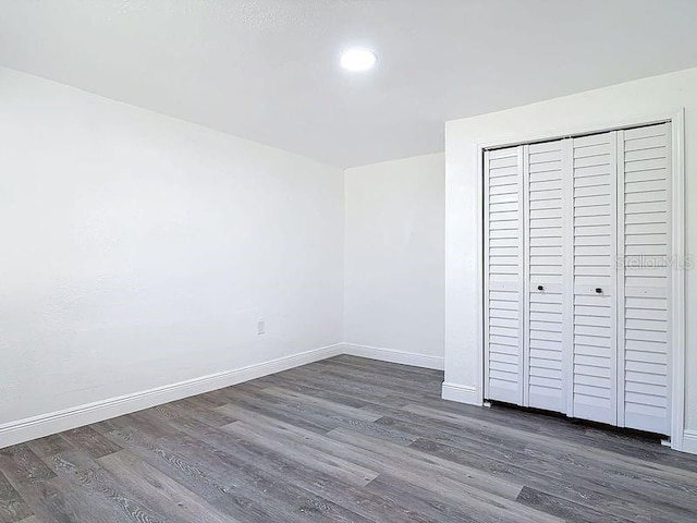 unfurnished bedroom with dark wood-type flooring, recessed lighting, a closet, and baseboards