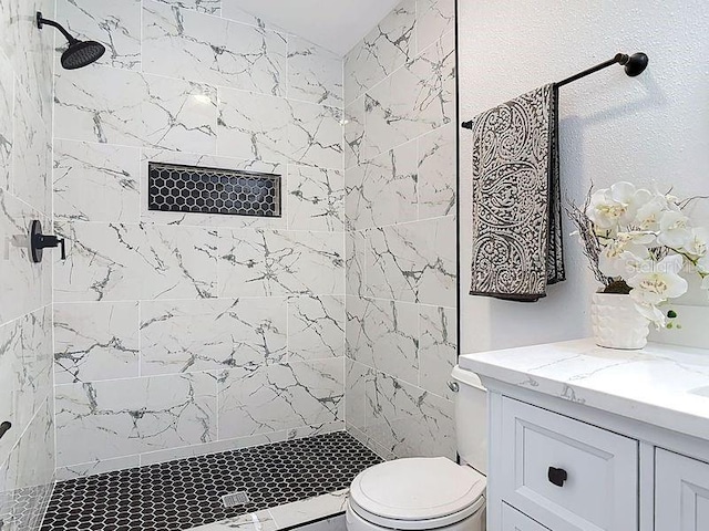 full bath featuring tiled shower, vanity, and toilet