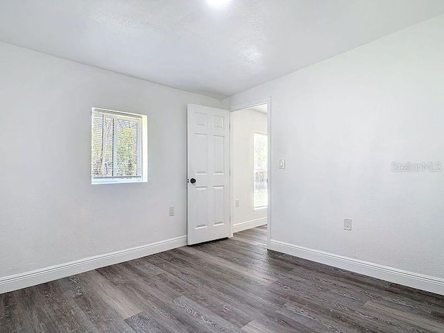 empty room featuring a healthy amount of sunlight, baseboards, and wood finished floors