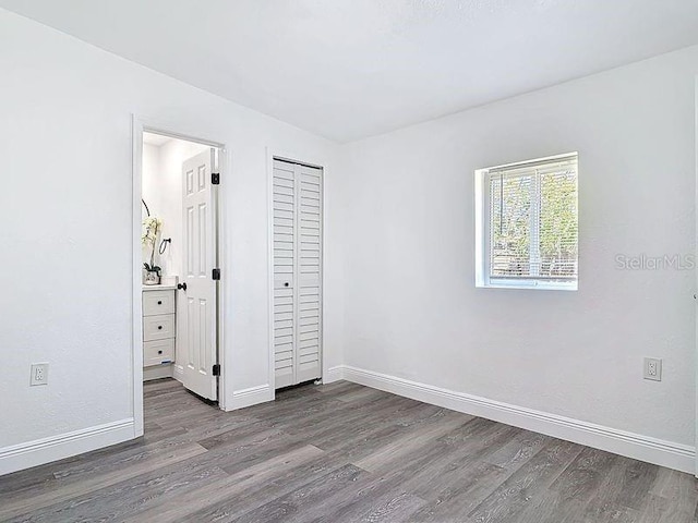 unfurnished bedroom featuring a closet, baseboards, and wood finished floors