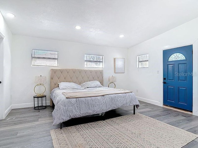 bedroom with a textured ceiling, wood finished floors, and baseboards