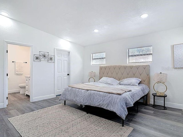 bedroom with baseboards, ensuite bath, wood finished floors, vaulted ceiling, and a textured ceiling