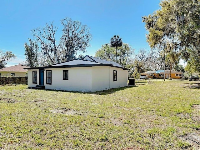 view of side of property with a yard, fence, and stucco siding