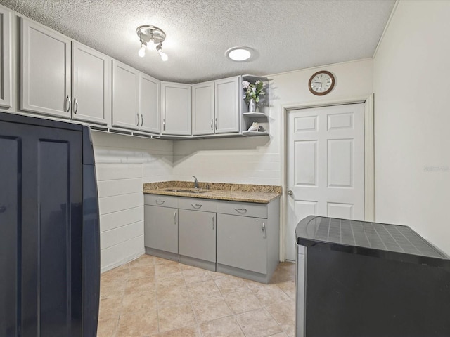 kitchen featuring light tile patterned flooring, open shelves, a textured ceiling, and a sink