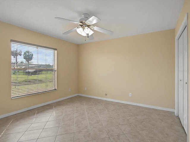 unfurnished bedroom with a closet, light tile patterned floors, a ceiling fan, and baseboards