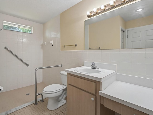 full bathroom with vanity, a tile shower, tile patterned flooring, tile walls, and toilet