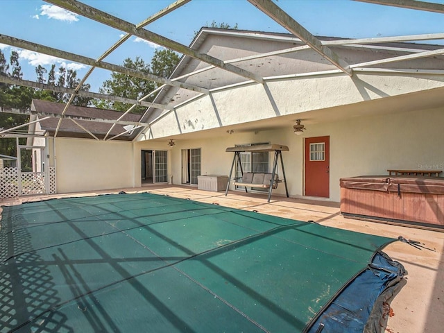 view of swimming pool featuring glass enclosure, a patio area, a ceiling fan, and a hot tub