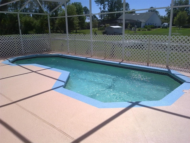 view of swimming pool featuring a lanai, fence, a fenced in pool, and a patio