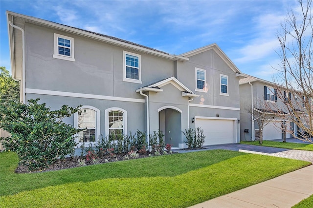 view of front facade featuring a front yard, an attached garage, driveway, and stucco siding