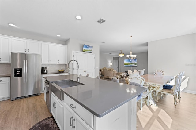 kitchen featuring visible vents, a sink, tasteful backsplash, dark countertops, and stainless steel fridge with ice dispenser