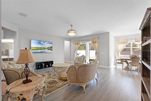 living room with an inviting chandelier, wood finished floors, and visible vents