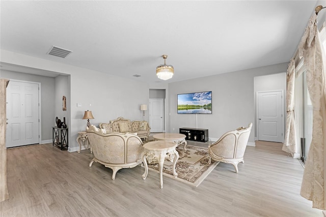 living room featuring light wood finished floors, visible vents, and baseboards