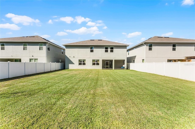 rear view of property with stucco siding, a lawn, and a fenced backyard