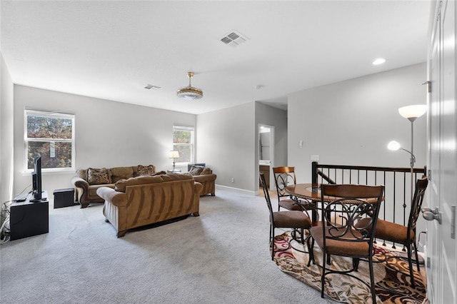 living area with light colored carpet, visible vents, and baseboards