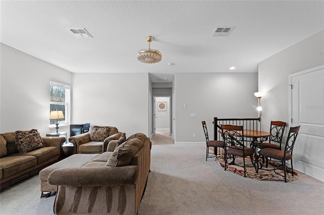 living area featuring visible vents, light colored carpet, a textured ceiling, and baseboards