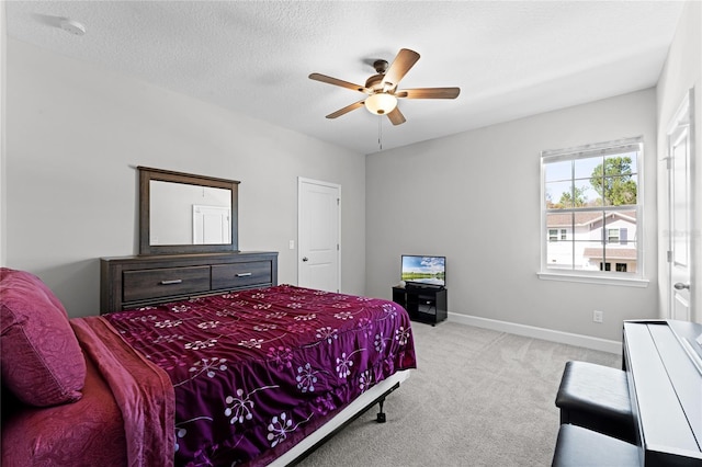 bedroom featuring a textured ceiling, ceiling fan, baseboards, and light carpet