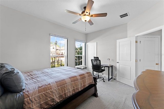 bedroom featuring a ceiling fan, visible vents, and light carpet