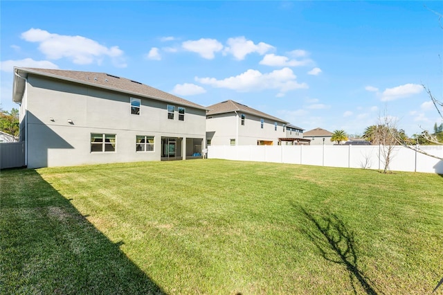 rear view of property with a yard, fence, and stucco siding