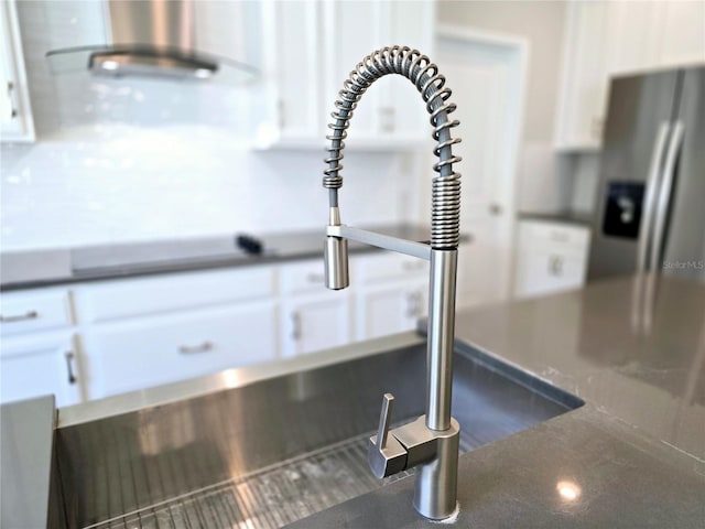 room details featuring a sink, dark countertops, and white cabinetry