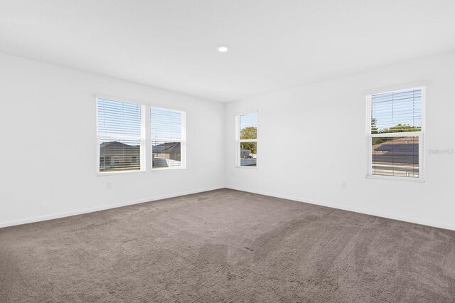 carpeted empty room featuring baseboards