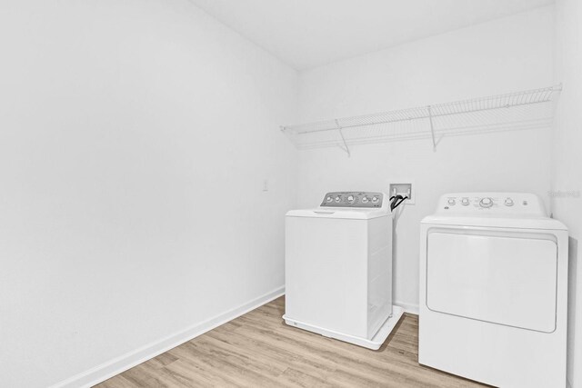 washroom featuring washer and dryer, laundry area, light wood-style floors, and baseboards