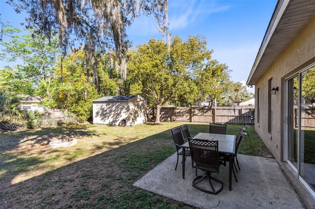 view of yard featuring an outbuilding, a shed, outdoor dining area, a fenced backyard, and a patio area