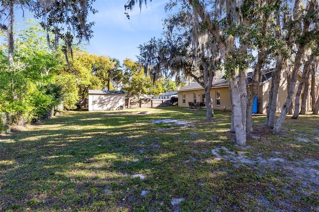 view of yard featuring an outbuilding, a storage unit, and fence