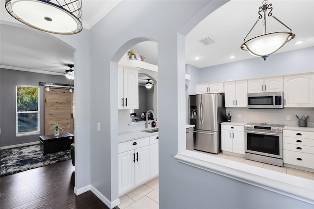 kitchen with appliances with stainless steel finishes, ceiling fan, light countertops, and ornamental molding