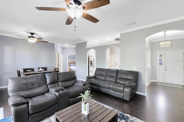 living area featuring visible vents, baseboards, arched walkways, ornamental molding, and dark wood-type flooring