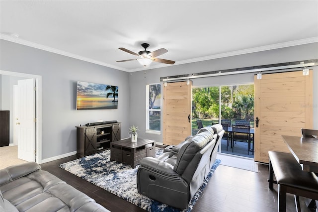 living area with a barn door, baseboards, wood finished floors, and crown molding