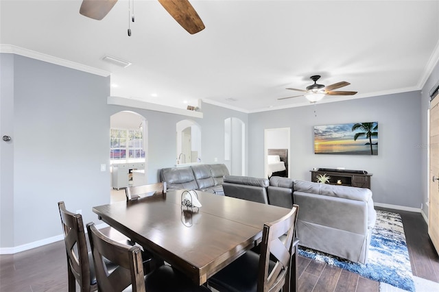 dining room with arched walkways, dark wood-style flooring, and crown molding