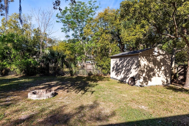 view of yard with a storage shed, an outdoor structure, and an outdoor fire pit