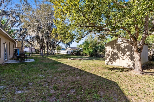 view of yard with an outbuilding, a storage shed, a fenced backyard, and a patio area