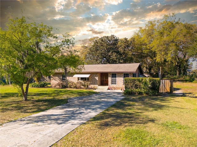 view of front of property featuring brick siding, a lawn, entry steps, and concrete driveway