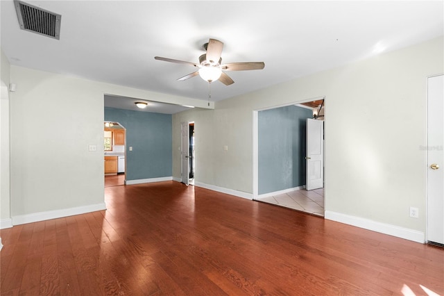 spare room with arched walkways, visible vents, baseboards, and wood finished floors