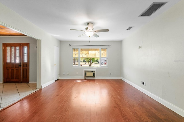 interior space featuring ceiling fan, visible vents, baseboards, and wood finished floors