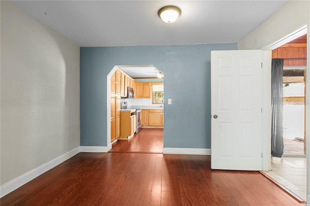 interior space with arched walkways, dark wood finished floors, and baseboards