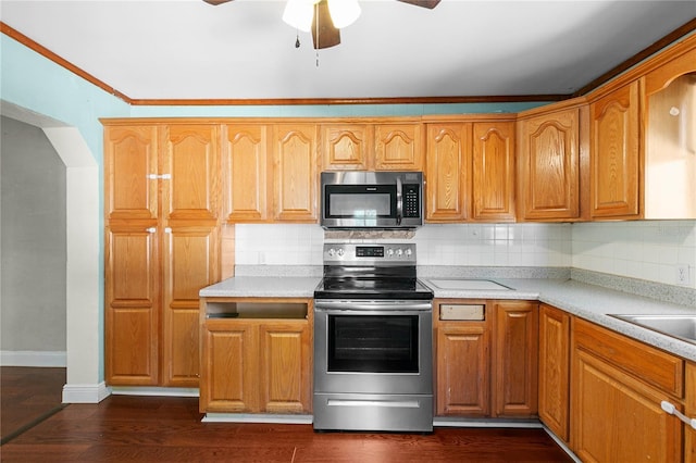 kitchen with dark wood-style flooring, ceiling fan, stainless steel appliances, light countertops, and backsplash