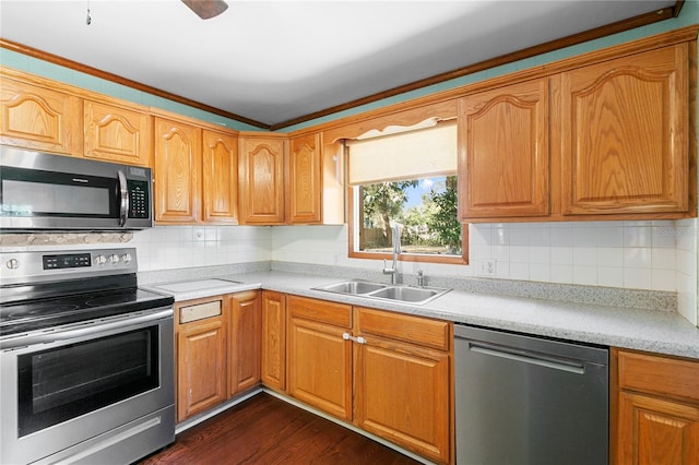 kitchen with dark wood finished floors, light countertops, decorative backsplash, stainless steel appliances, and a sink