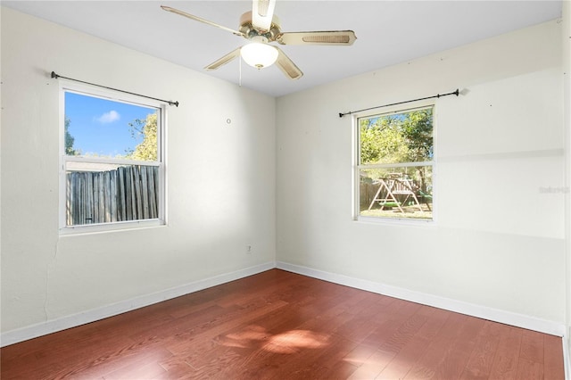 empty room with wood finished floors, baseboards, and a wealth of natural light