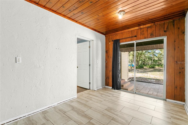 unfurnished room featuring wood ceiling, baseboards, and a textured wall