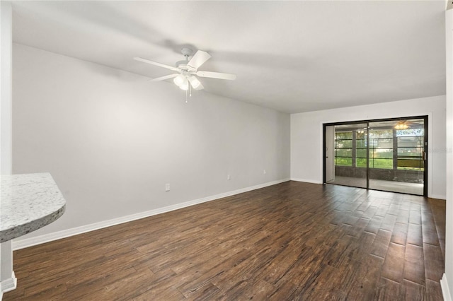 spare room featuring a ceiling fan, baseboards, and dark wood-style flooring