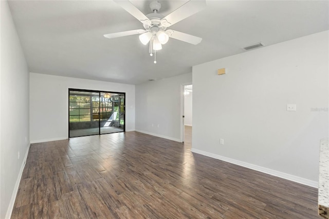 spare room featuring dark wood-type flooring, a ceiling fan, baseboards, and visible vents