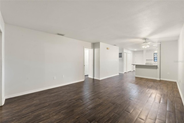 unfurnished living room featuring a ceiling fan, dark wood-style floors, visible vents, and baseboards