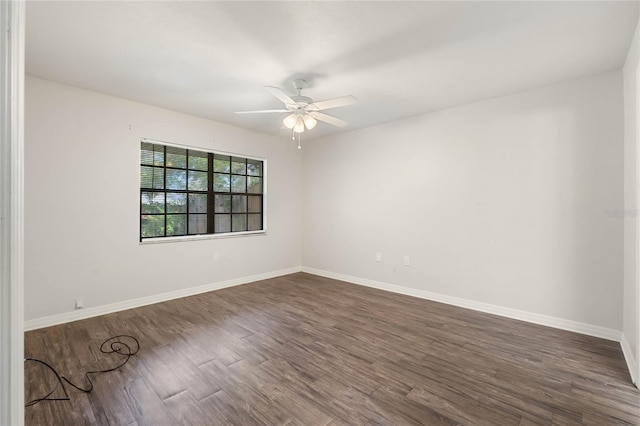 empty room featuring baseboards, dark wood-style floors, and a ceiling fan