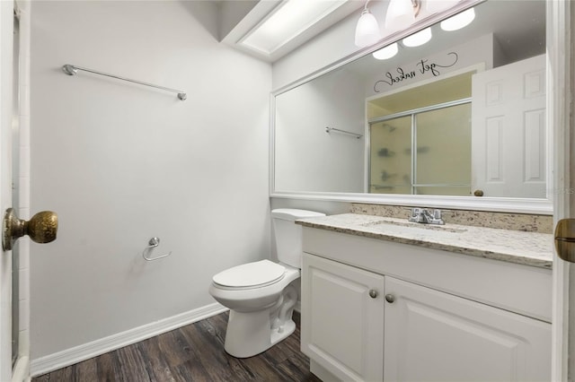 full bath with toilet, a stall shower, wood finished floors, baseboards, and vanity